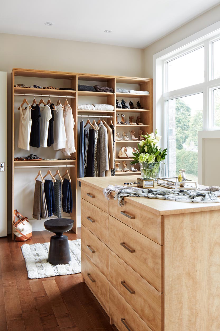 A beautifully designed clutter free walk in closet with cabinetry, clothes and accessories.