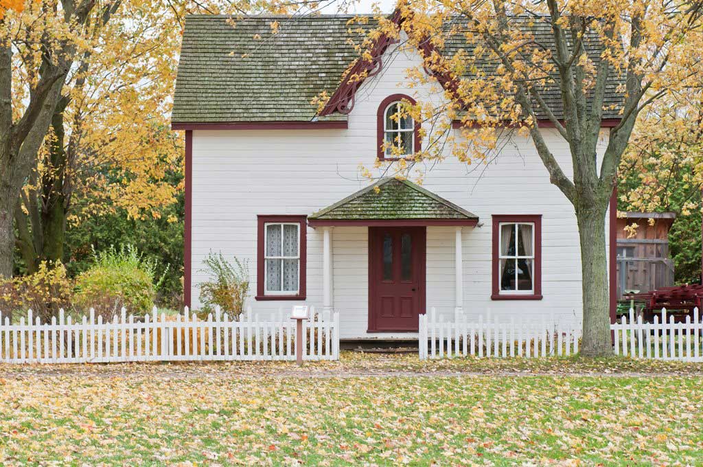 Quaint country home with white picket fence in fall season.