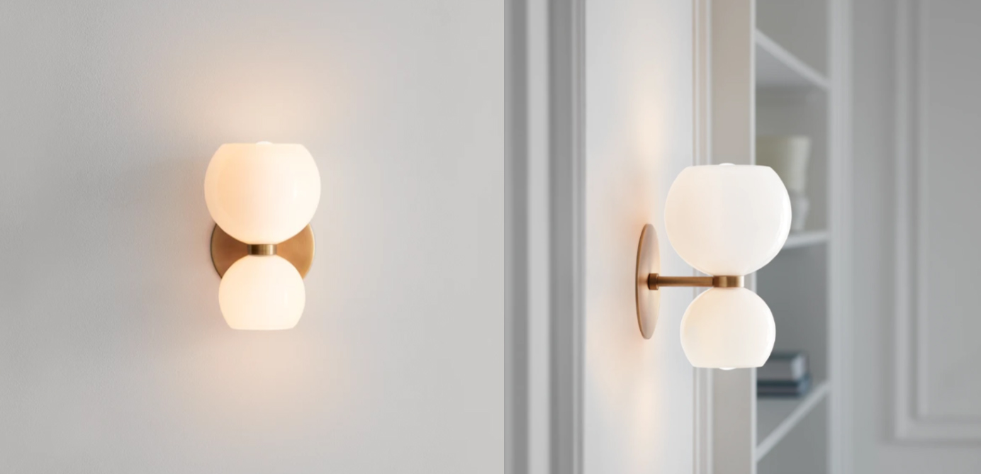 A modern wall sconce with a brass backplate and two spheres of white glass stacked on top of each other.
