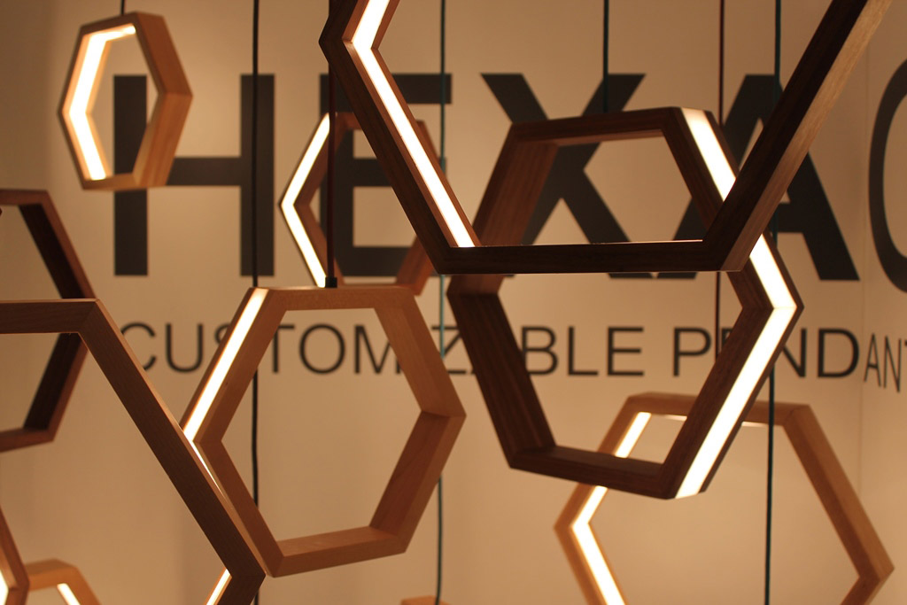 Multiple hexagon shaped lights made from LED and wood hanging in a display.