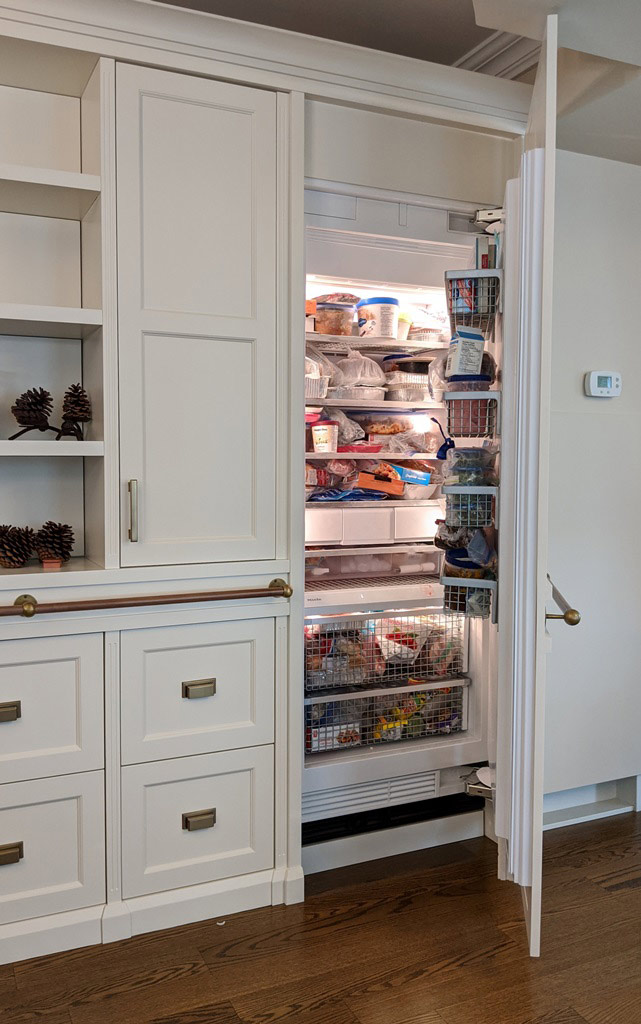 Transitional style white custom-built cabinetry, showing a view with the built-in freezer door open.
