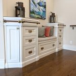 Transitional style white custom front entry cabinet with built in bench seating, decorative railing, and drawer storage.