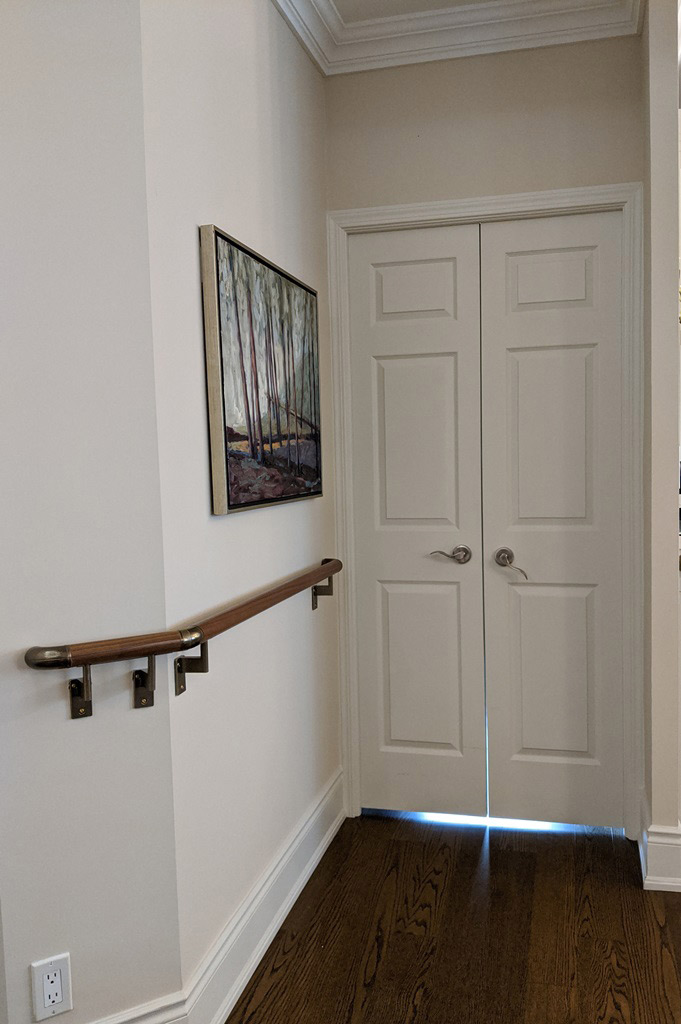 A section of hallway with a custom grab bar installation mounted to the wall and a double door entry into the adjacent office.