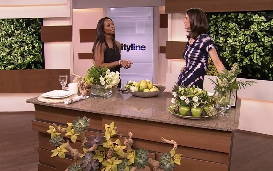 Celia Alida Rutte and Tracy Moore on the Cityline set with fruit and floral centerpieces on display.